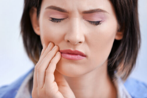 woman holding side of her mouth