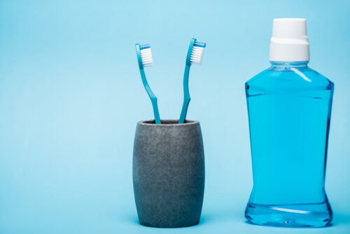 Toothbrushes and bottle of oral mouthwash on blue background