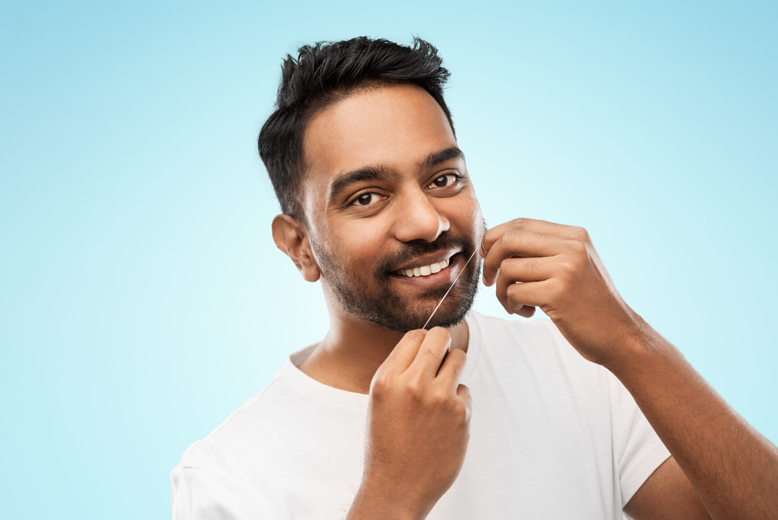 man with dental floss cleaning teeth