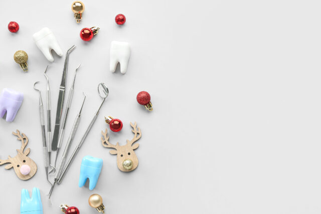 Dental tools with plastic teeth and Christmas toys on light background