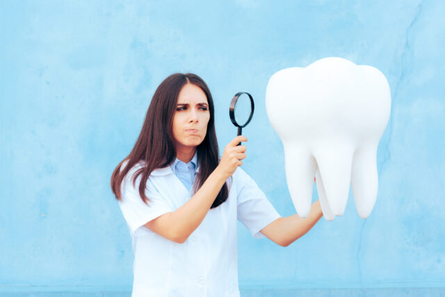 woman looking at big tooth with magnifying glass