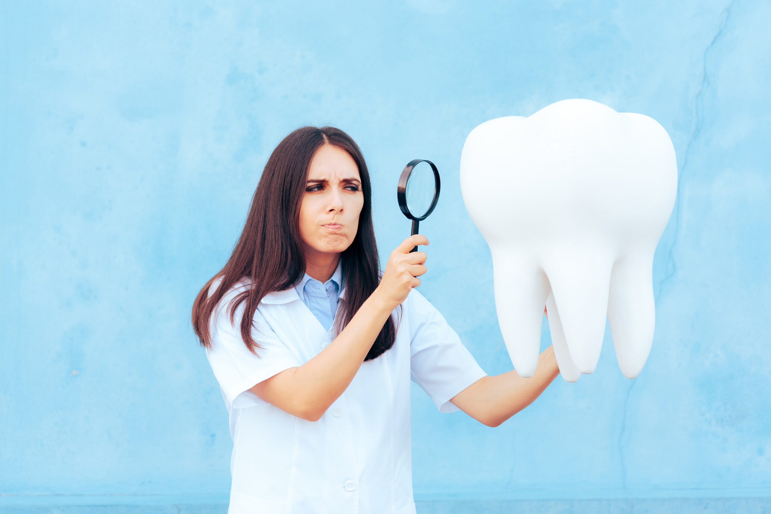 woman looking at big tooth with magnifying glass