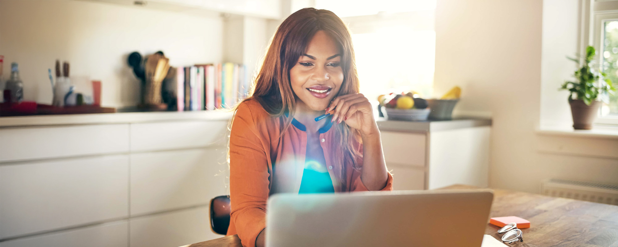 Smiling young female entrepreneur working online at her kitchen