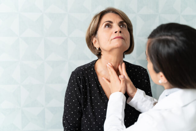 Caucasian woman visiting female geriatrician for thyroid checkup