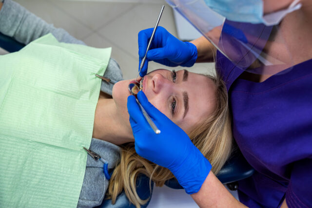 a regular client comes to the dentist to whiten and grind the brushing routine at her woman's dentist. The concept of healthy white teeth.