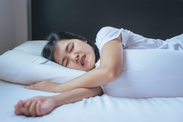 Female sleeping on the bed and grinding teeth,Tiredness and stress.